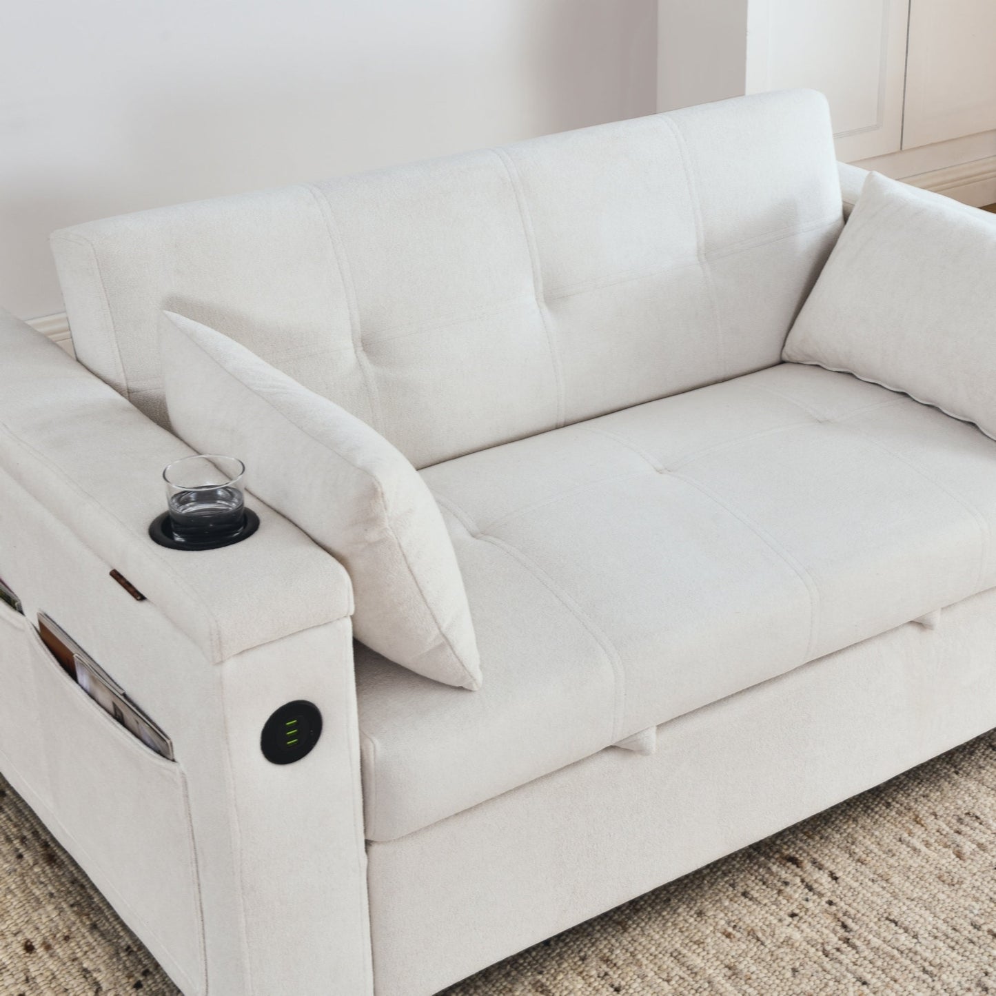 Divano letto reclinabile a due posti con braccioli, contenitore e tasche laterali, con presa di corrente USB.