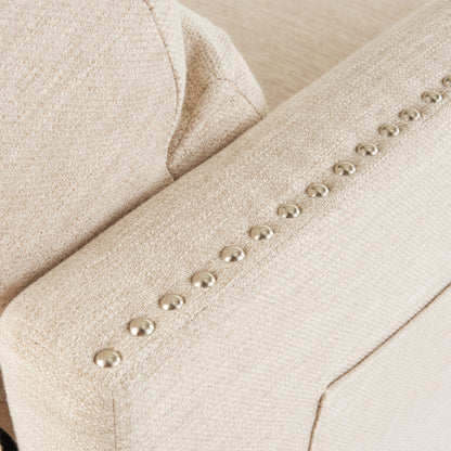 Poltrona reclinabile moderna in tessuto beige con poggiapiedi, dettagli con borchie e gambe in legno di betulla